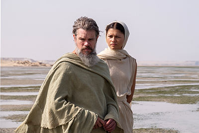 Matt Damon als Odysseus und Zendaya als Athene spazieren den Strand entlang