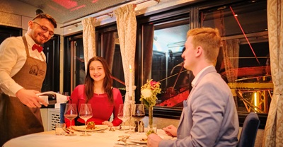 Kellner schenkt einem Pärchen Wein ein bei einem Dinner im Wiener Riesenrad