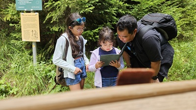 Familie schaut in Notizbuch beim Outdoor Escape Game für Kinder in Mitterbach