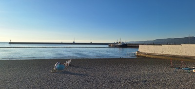 Im Frauenbereich am Kiesstrand von La Lanterna in Triest: Einige Strandstühle stehen herum, das Meer ist ruhig.