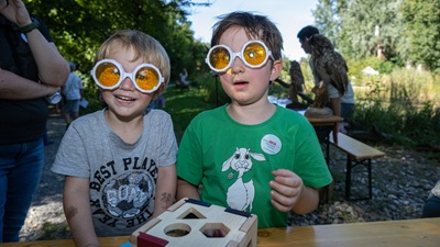 Zwei Kinder mit einer Brille, die Facettenaugen simuliert bei einer Mitmachstation beim Familientag auf der Schlossinsel in Orth.