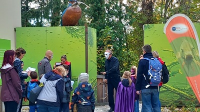 Verkleidete Familien und Mann mit weißer Maske bei einer Halloween-Führung beim Eingang der Schlossinsel.