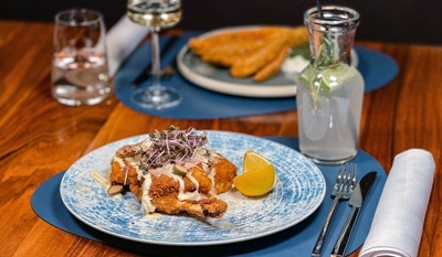 Kalbsschnitzel und Melanzani paniert im Handwerk Restaurant auf dem Teller