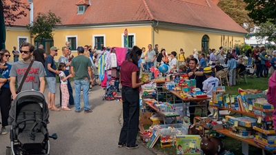 Familien vor den Ständen beim Viennergy Herbstfest mit Kinderflohmarkt vor dem Europahaus in Wien - volle Tische mit alten Spielen
