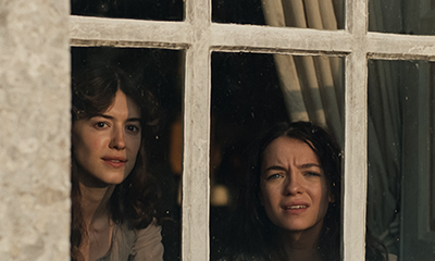 Daisy Edgar-Jones als Elinor Dashwood und Esmé Creed-Miles als Marianne Dashwood beobachten wohl durch das Fenster ihre Freier in SINN UND SINNLICHKEIT (c) Universal Pictures