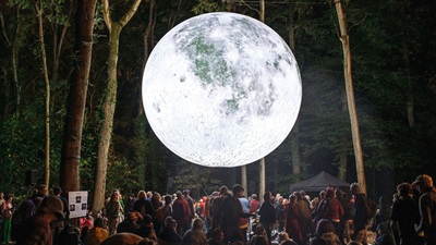 Lichtinstallation eines leuchtenden Mondes direkt über Menschen