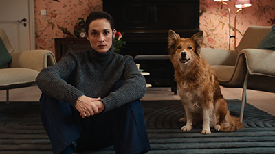 Friederike Becht und ihr Hunde-Filmpartner sitzen in der Netflix-Serie Die Falle in einem Wohnzimmer am Boden mit Blick Richtung Kamera