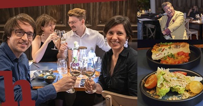 Zwei Pärchen stoßen im Wiener Handwerk Restaurant auf einem Tisch auf die Wine-Battle an. Zwei Speisen und Matt Schuh am Klavier.