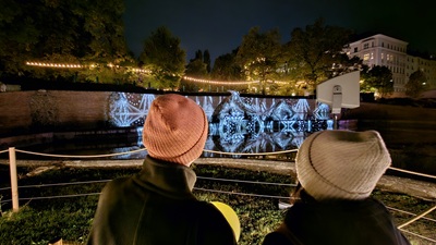 Zwei Frauen mit Mütze stehen vor dem Brunnen im Schwarzenberggarten und einer Lichtinstallation