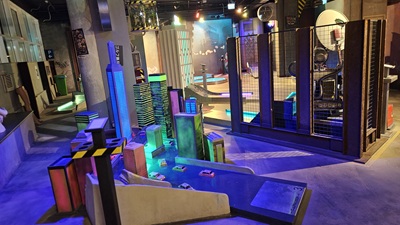 Bunt in Neonfarben beleuchtete Miniatur-Hochhäuser in einer Cyberpunk-Minigolfwelt.