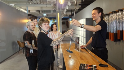 Mann reicht einer Frau einen Minigolfschläger über den Tisch im Auhof Center