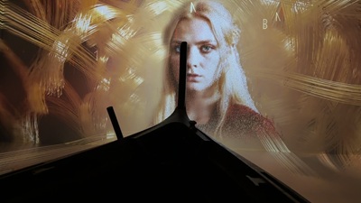 Blonde Frau vor einem Schiffsrumpf in der immersiven Wikinger-Ausstellung in Wien.