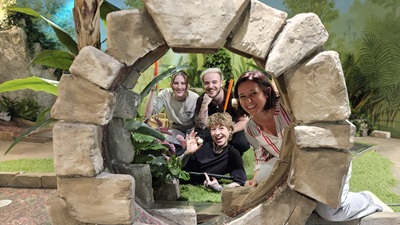 Drei Frauen und ein Mann schauen durch ein Looping in einer Minigolf-Dschungelwelt
