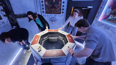 3 Frauen und ein Mann um eine Art Brunnen, der ein Rätsel im Escape Room The Temple ist.